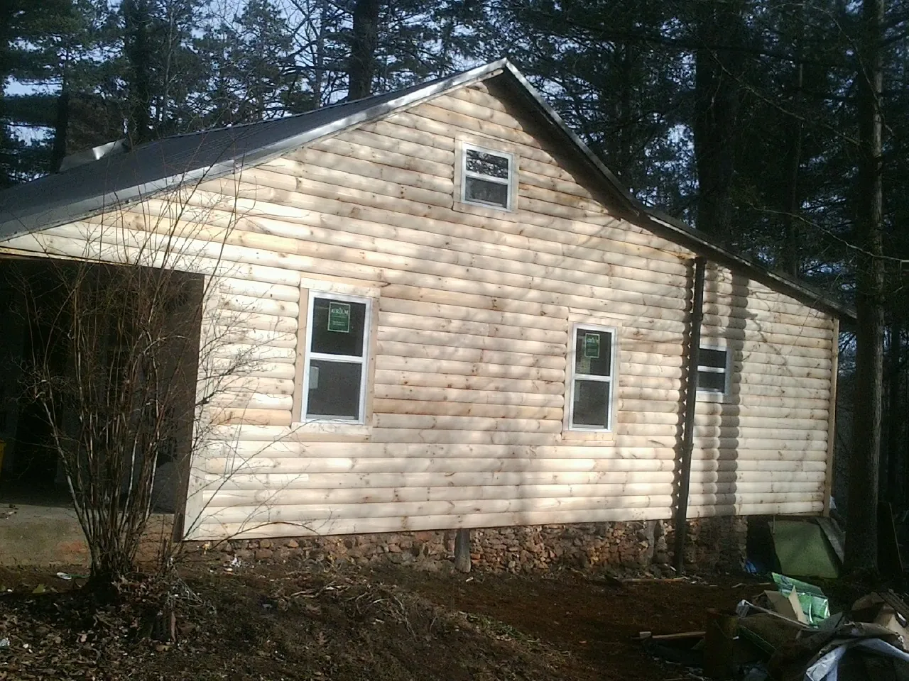 New log siding and dark metal roofing on a gable end in Aylett
