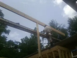 Carpenter setting a ridge beam over a new addition frame — Ice Dam Removal by Roofing Brothers in Aylett