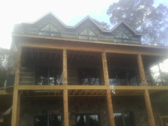 Dormers and porch framing on a large log home under construction — Roof Coating work by our crew in Aylett
