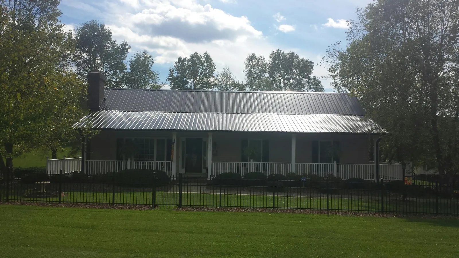 Gray metal roof on a brick ranch with a full width front porch — Gutter Guard Installation work by our crew in Aylett