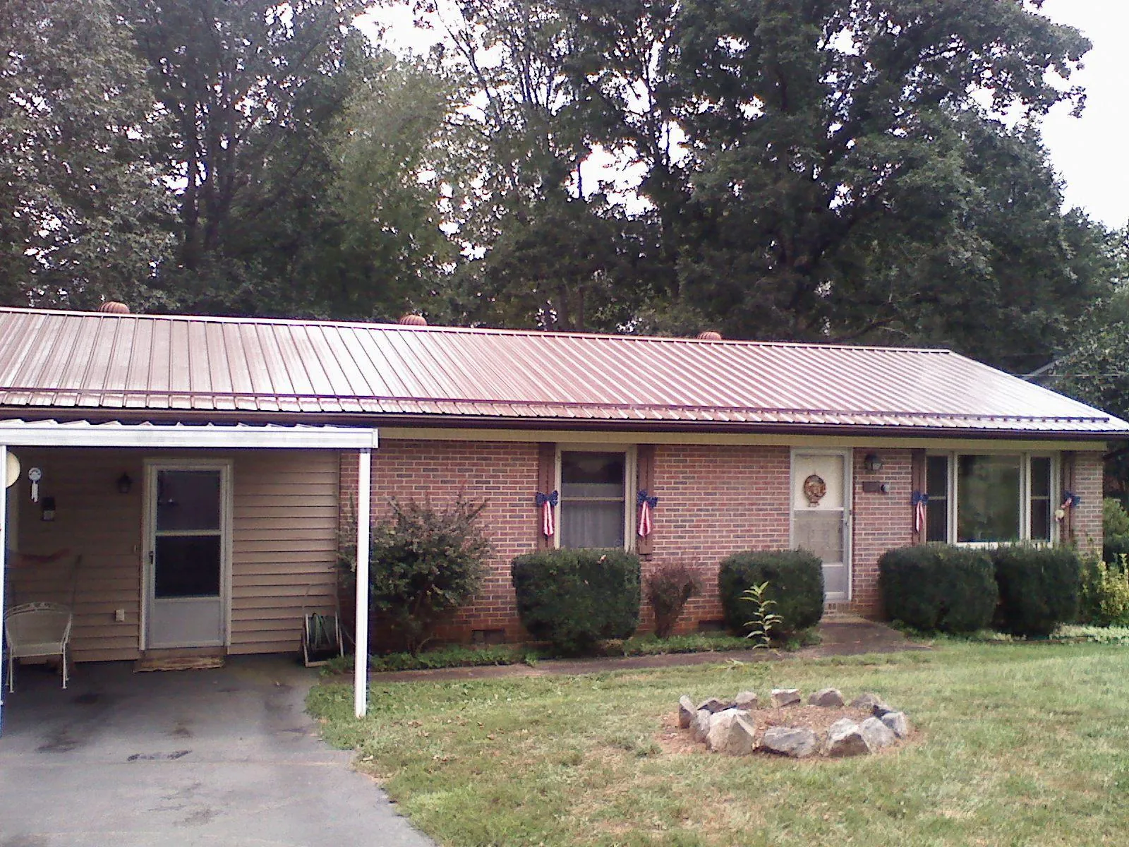 Bronze metal roof and carport on a brick ranch home — Roof Repair work by our crew in Aylett